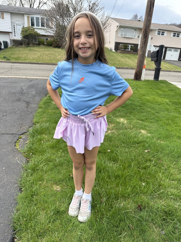 A happy customer posing with her new blue SPEEDY t-shirt with orange icon